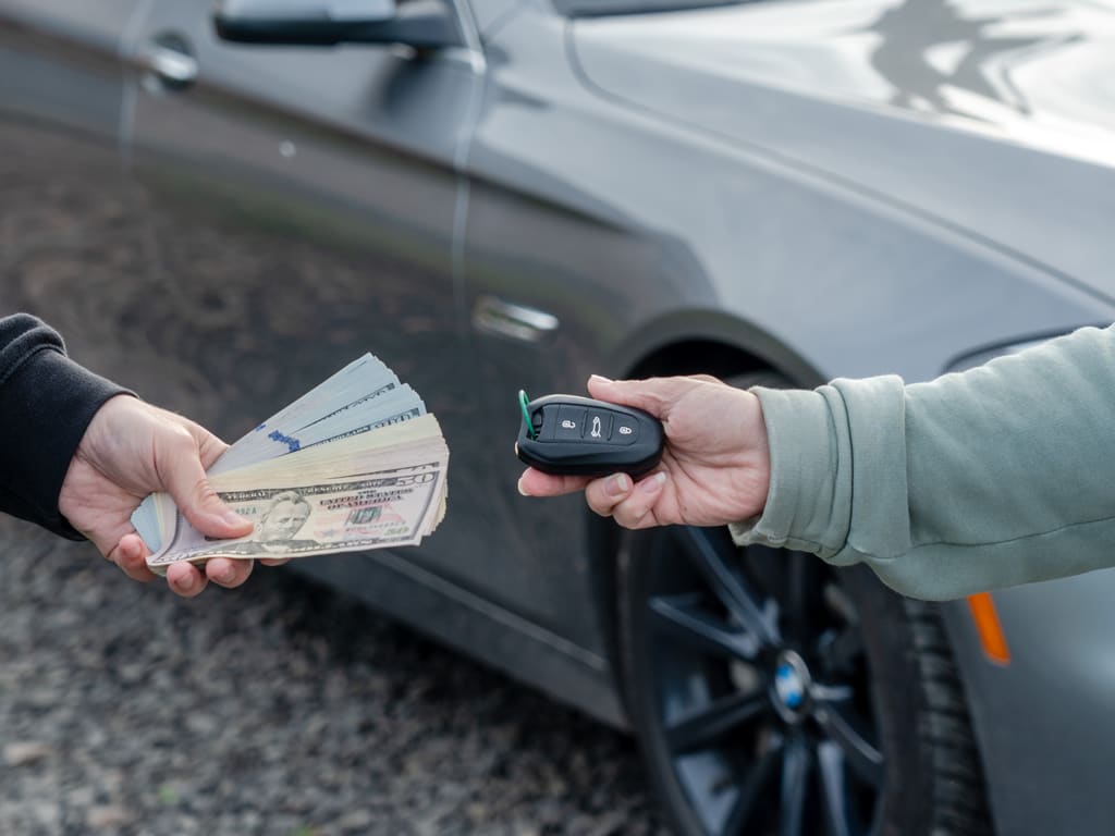 A seller exchanging car keys for cash beside a vehicle